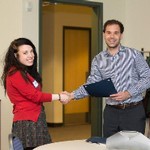 Presenter shaking hands with woman during certificate presentation both are smiling